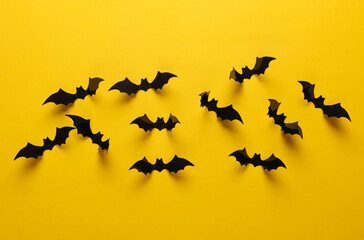 Halloween decoration concept. Black paper bats flying on yellow background. Top view