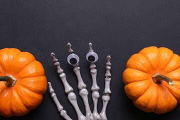 Halloween decoration concept. Plastic skeleton hands and decor on black background. Flat lay.
