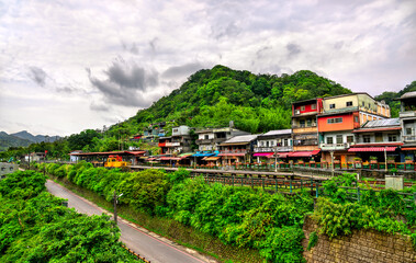 Colorful houses and shops line the tracks of the historic Pingxi railway in Shifen Village, nestled among forested hills in New Taipei, Taiwan. This popular destination is known for its lantern