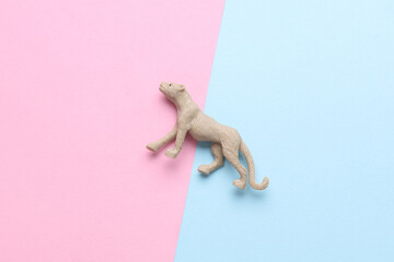 Plastic toy cheetah figurine on blue pink background