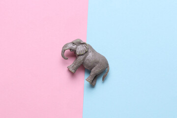 Plastic toy elephant figurine on blue pink background
