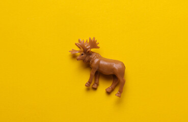Plastic toy moose figurine on yellow background