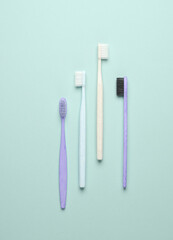 Plastic and eco bamboo toothbrushes on blue pastel background. Top view