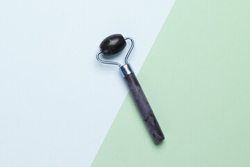 Jade massage roller for anti-aging face lifting on a pastel background. Minimalism beauty still life