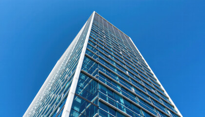 Modern skyscraper with glass facade reaches towards clear blue sky, showcasing its sleek design and architectural elegance. building reflective surface captures sunlight beautifully, creating