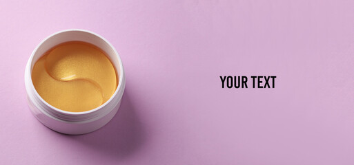 Jar with golden eye patches on purple background. Beauty concept. Space for your text