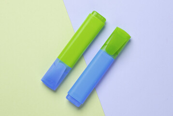 Blue and green markers on pastel background