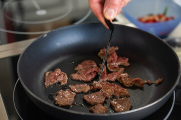 The chef fries veal in a frying pan. 