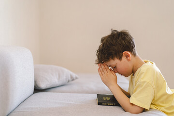 Fototapeta premium A boy with folded hands in front of him, he is praying or meditating. Concept of Christianity, religion and faith.