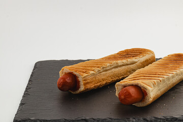 Hot dogs served on a dark slate plate for a casual meal