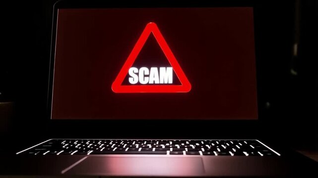 A "Scam Alert" warning appears on the laptop screen, urging the user to stay cautious.
