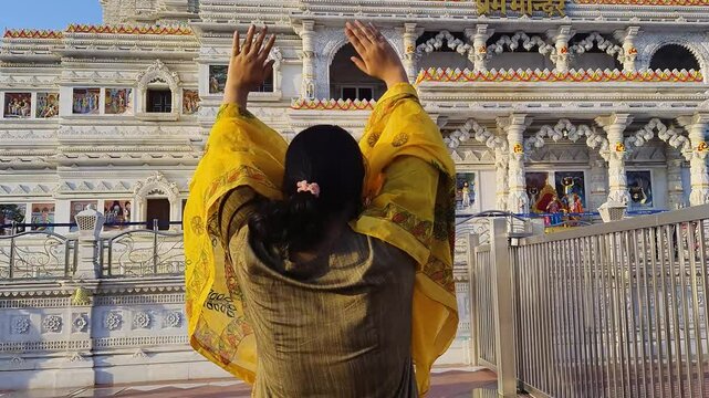 devotee praying at ancient white marble hindu temple at day from back