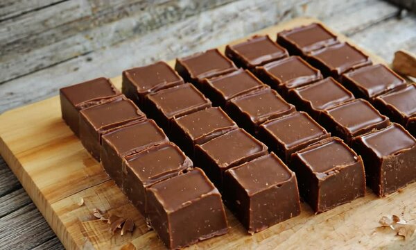 Deliciously arranged chocolate fudge squares on a rustic wooden cutting board