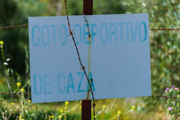 Weathered sign reading coto deportivo de caza marks a designated hunting area in the spanish countryside