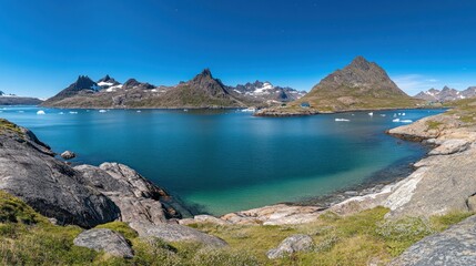 Fototapeta premium Panoramic view of a serene fjord in Greenland, featuring turquoise water, rocky shores, snow-capped mountains, and icebergs.