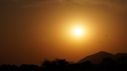 Glowing sun behind distant hills in vibrant sky