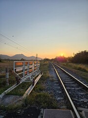 railroad tracks in countryside with blue sky in evening while sunlight is going down