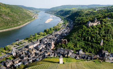 Aerial drone view of Bacharach, historic German town in the UNESCO Upper Middle Rhine Valley. Features Stahleck Castle, Wernerkapelle ruins, St. Peter's Church, vineyards, and the Rhine River.