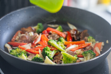 Beef and vegetables are fried in a frying pan. 
