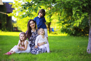 Obraz premium Young large family on a summer morning walk. Beautiful mother with children is playing in the park.