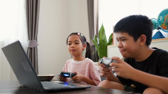Asian teenage boy and girl playing video games at home together. Concept of digital lifestyle, esports, fun learning, teamwork, and modern entertainment for kids and teens indoors.