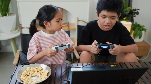 Asian teenage boy and girl playing video games at home together. Concept of digital lifestyle, esports, fun learning, teamwork, and modern entertainment for kids and teens indoors.