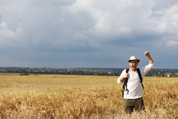 Tourist in a field of cereal plants. A man in a wheat field. Grain harvest.
