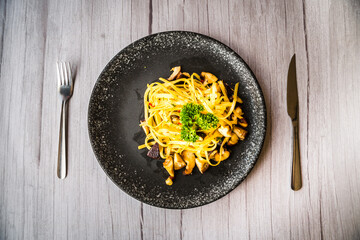 Mushroom Aglio Olio pasta served on a black plate on a table