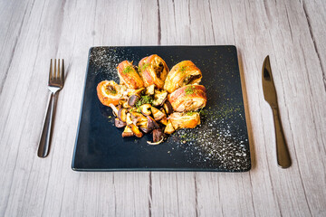 chicken roulade with sauteed mushrooms served on a black platter