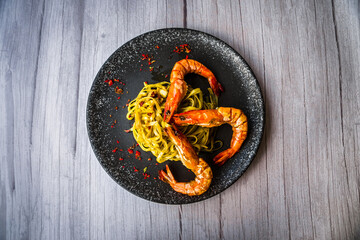Chimichuri Pasta with Tiger Prawn served on a black plate