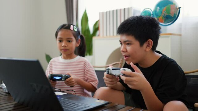 Asian teenage boy and girl playing video games at home together. Concept of digital lifestyle, esports, fun learning, teamwork, and modern entertainment for kids and teens indoors.