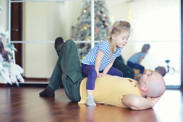 Family vacation, happy father and little daughter relaxing on the floor together