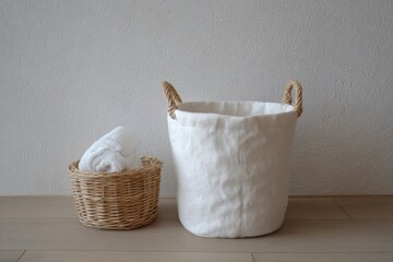 Fototapeta premium Minimalist Still Life of Laundry Baskets with Towel on Wood Floor Against Textured Wall Neutral Tones Clean Aesthetic