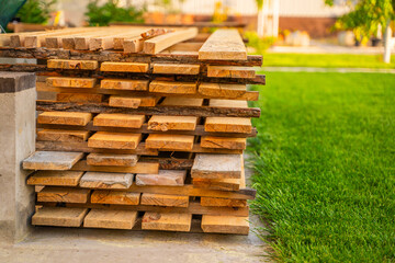 Wooden construction boards close-up stacked near green lawn grass