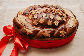 traditional loaf of bread wrapped in a red ribbon lies on a white table, bread for meeting the...
