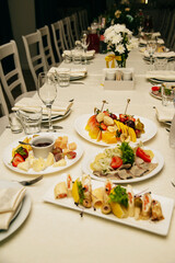 on a table covered with a white tablecloth there are various dishes and flowers for decoration for a wedding or birthday celebration, white chairs stand around the table