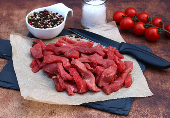 Beef strips: Raw beef cut into strips arranged with tomatoes and spices.