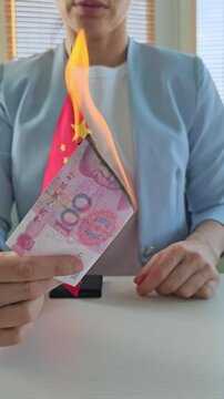Woman discusses Chinese currency while holding national flag and money at a desk
