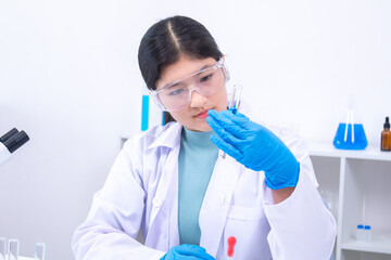 Teenage female student testing blue liquid with pipette in school laboratory. Science, laboratory,...