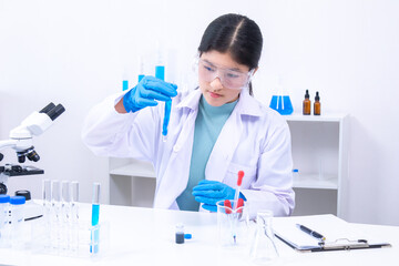 Young girl lifting glass tube and inspecting blue liquid inside. Science, laboratory, scientist,...