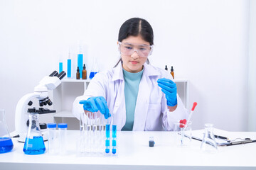 Fototapeta premium Female teen scientist holding test tubes and analyzing substance in clinical lab. Science, laboratory, scientist, experiment, and research represent accuracy, curiosity, and study atmosphere.