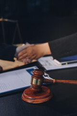 Two lawyers shaking hands after reaching an agreement during a legal trial, with scales of justice and gavel in the foreground