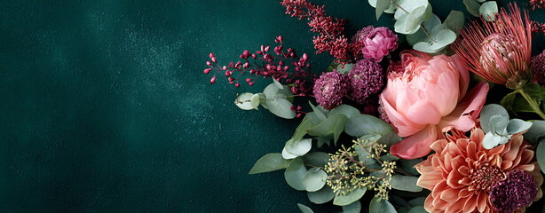 Autumn floral bouquet with dahlia, peony and vine leaves on a dark green textured surface, providing a place for text. Elegant design for a postcard or banner.