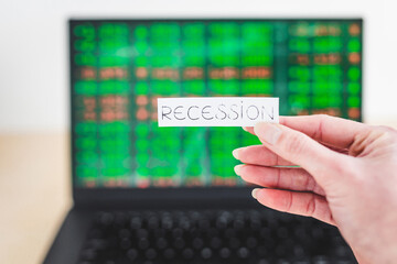 recession and stock market volatility after the pandemic, Recession text in front of computer screen with financal markets results