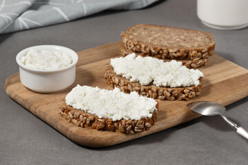 Delicious rye bread topped with cottage cheese on a wooden board in a modern kitchen setting