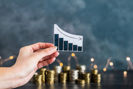 negative growth or bad business performance, graph with negative stats in front of stacks of coins with fairy lights