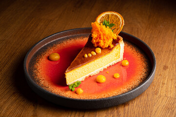 Enticing slice of pumpkin cheesecake garnished with fresh orange, carrot, and vibrant sauce