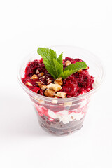 A vibrant layered dessert with raspberry topping, crunchy nuts, and a mint leaf garnish