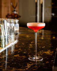 A vibrant red cocktail sits on polished marble, inviting relaxation and enjoyment