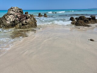 white sand, a few rocks and crystal clear water at the beach of plage de saleccia in corsica
